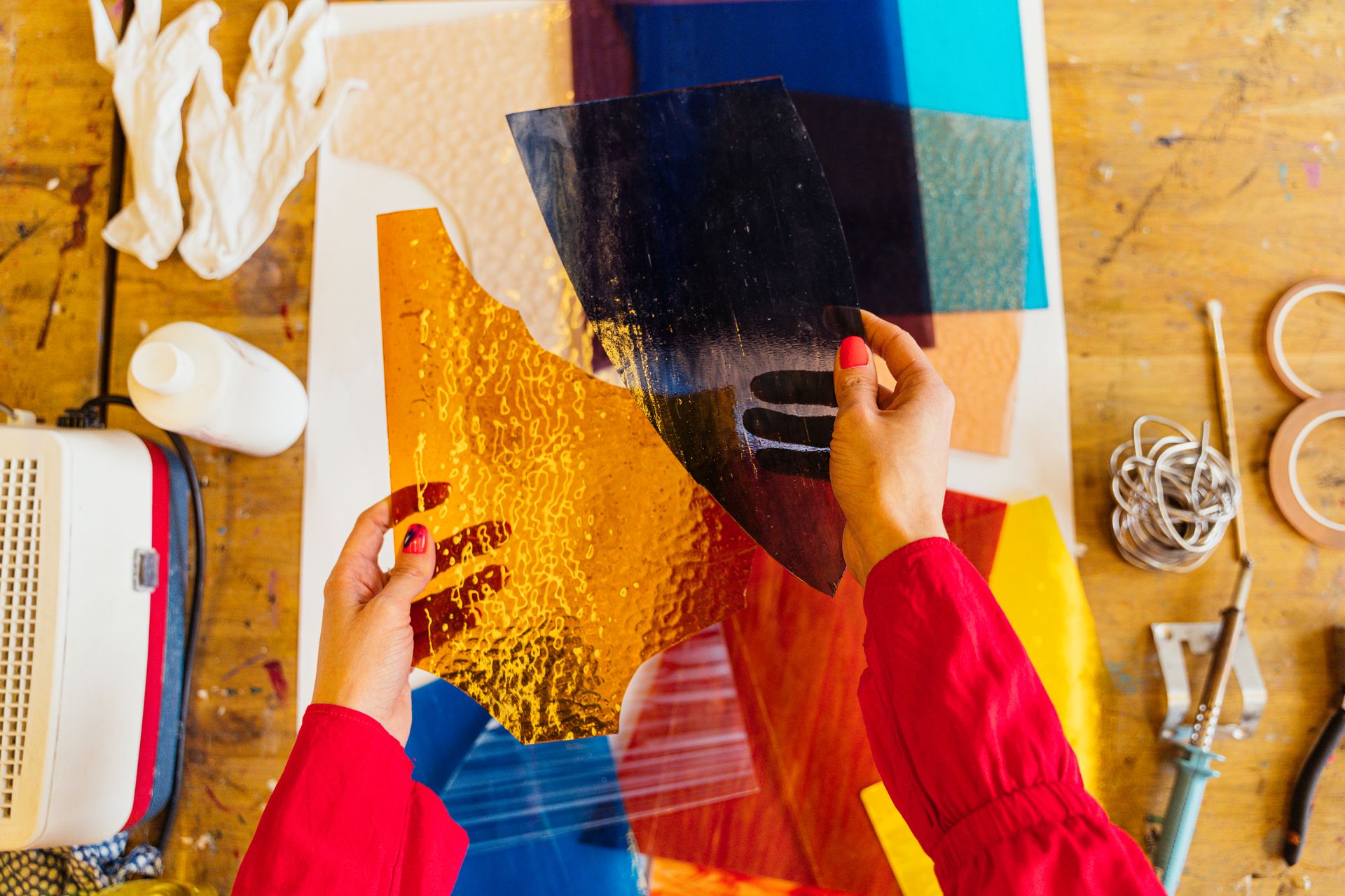 Hands hold vibrant stained glass pieces during artistic crafting session.