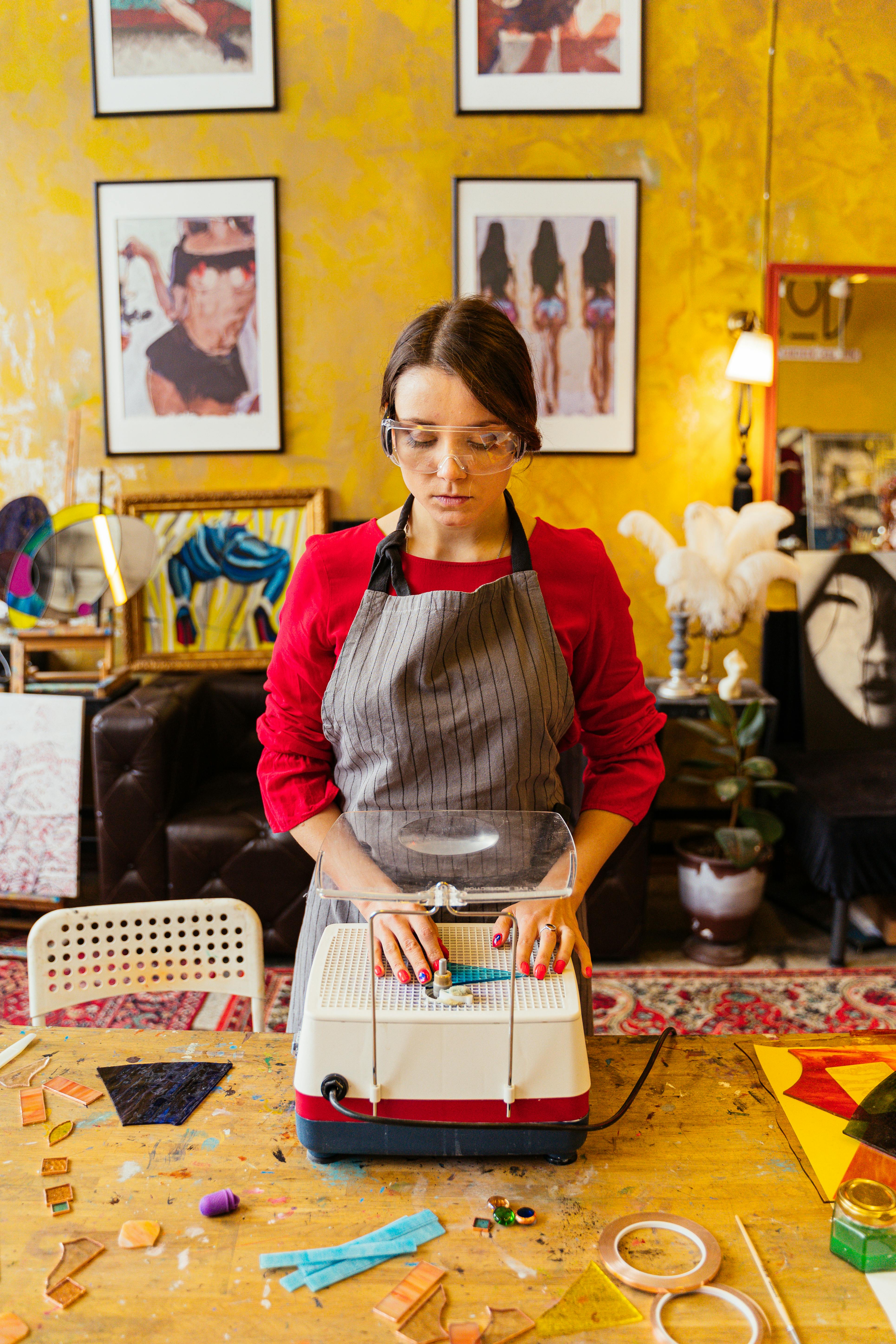 Female artist using a glass grinder machine in a vibrant art studio, demonstrating creativity and craftsmanship.