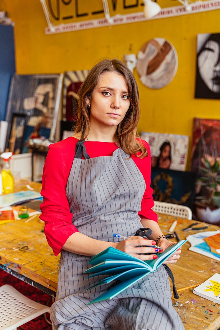 Woman In A Workshop Noting An Idea In Her Notebook 