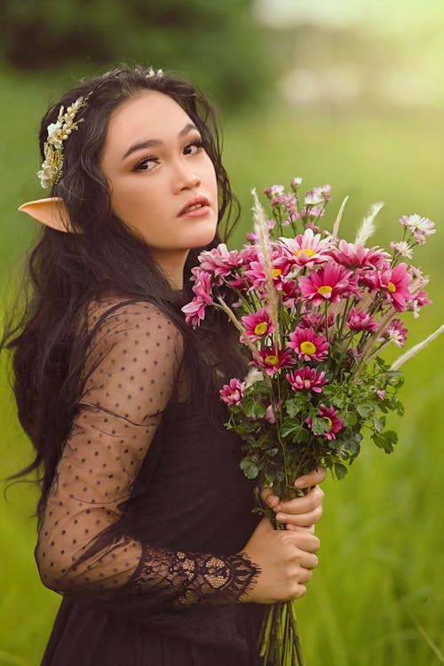 A Woman in Black See Through Long Sleeves Holding a Bouquet of Flowers