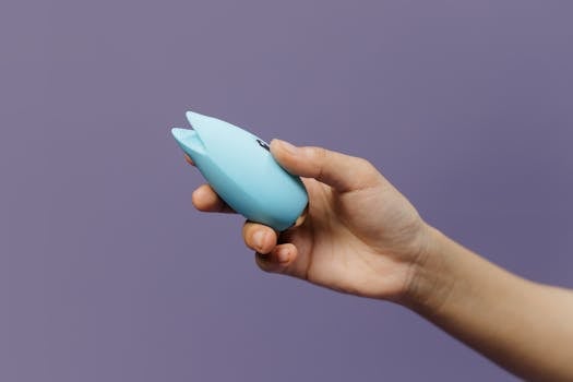 A blue silicone sex toy held in hand against a solid purple background, promoting self-love and sexuality.