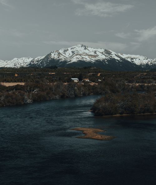 Free A serene view of a snow-capped mountain with a river flowing beneath it, showcasing nature's beauty. Stock Photo