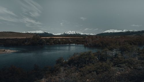 Free A tranquil lake scene with snow-capped mountains under a moody sky, perfect for nature lovers. Stock Photo