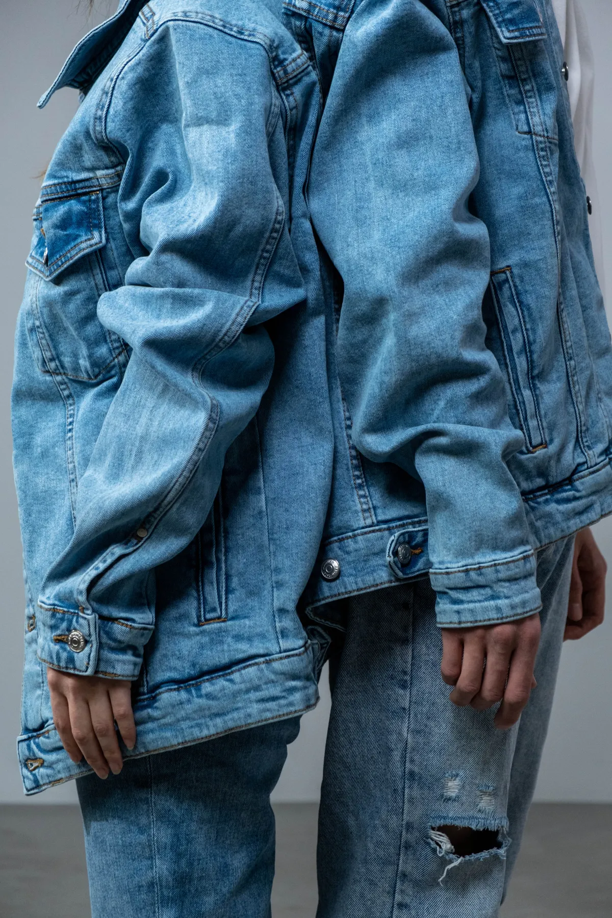 Layering dua jaket denim oversized warna biru muda untuk efek dimensi maksimal pada outfit