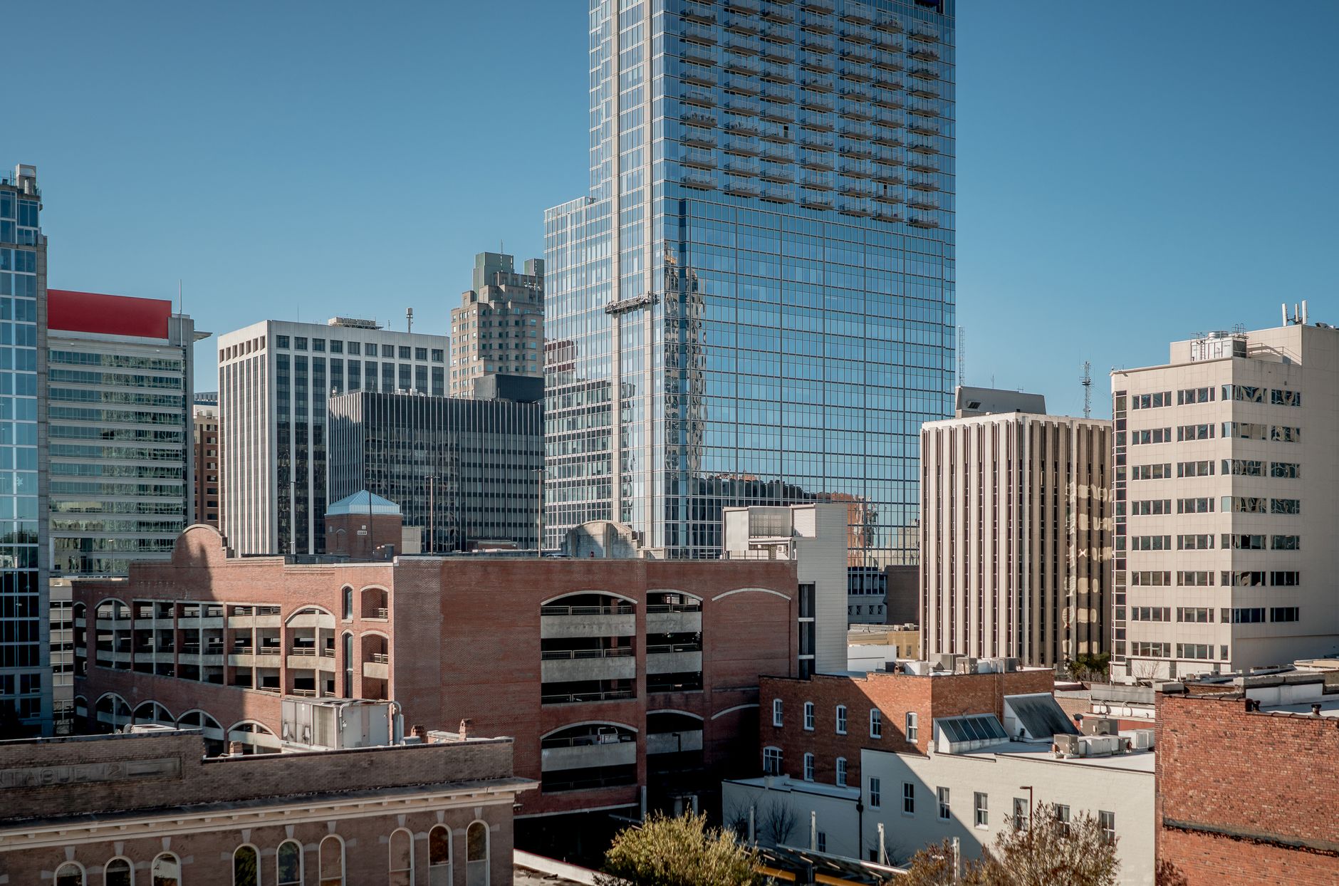 Aerial view of Raleigh, NC showcasing modern skyscrapers under a clear blue sky.