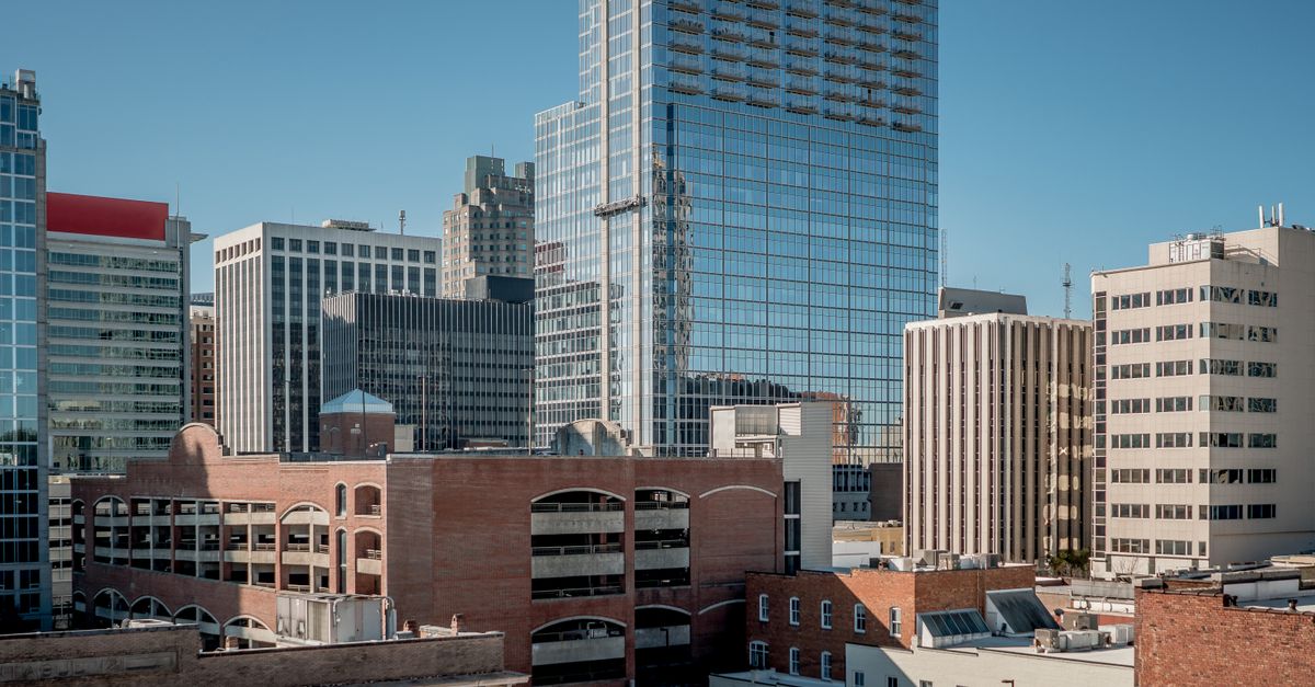 Aerial view of Raleigh, NC showcasing modern skyscrapers under a clear blue sky.