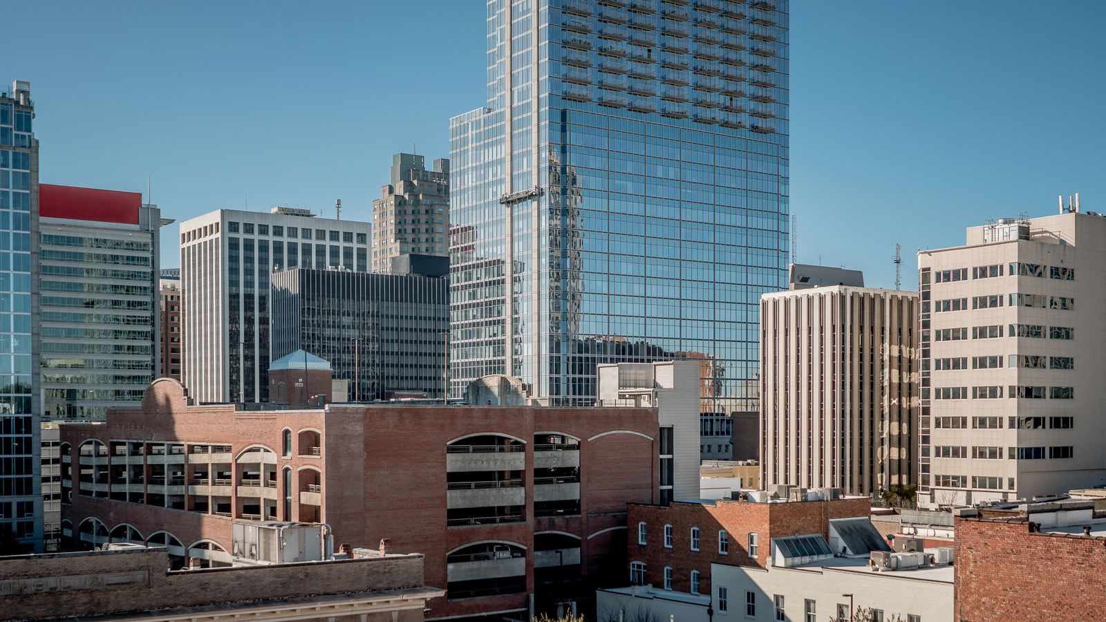 Aerial view of Raleigh, NC showcasing modern skyscrapers under a clear blue sky.