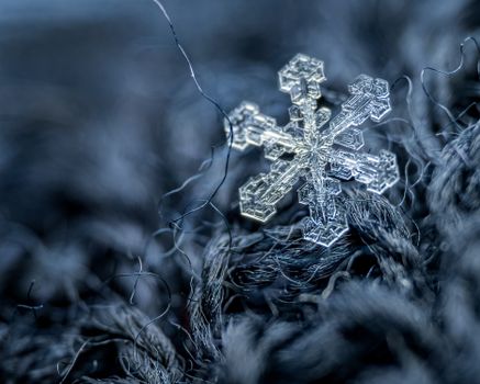 Small snowflake on woolen surface with fiber