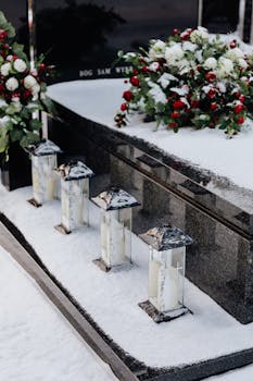 Elegantly adorned grave with lanterns and flowers in a snowy cemetery.