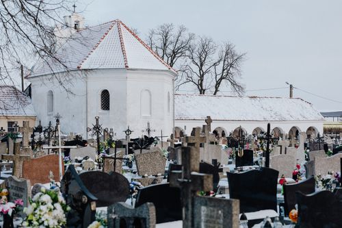 Free A serene winter scene of a snow-covered cemetery with tombstones and a chapel. Stock Photo