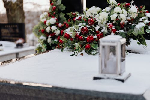 Flowers and a Candle on a Grave in Winter