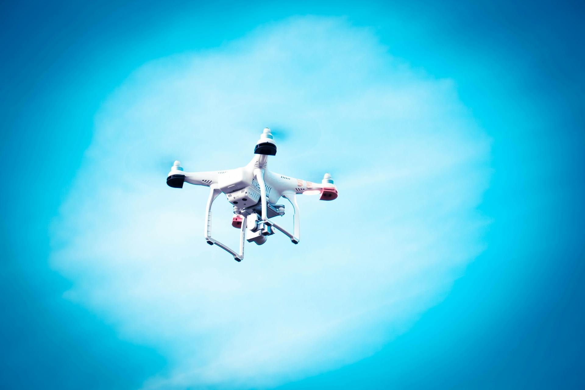 A white drone captured in flight under a bright blue sky, showcasing modern technology and innovation.