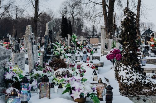 Free Snow-covered cemetery with colorful flowers and gravestones, evoking a serene winter atmosphere. Stock Photo