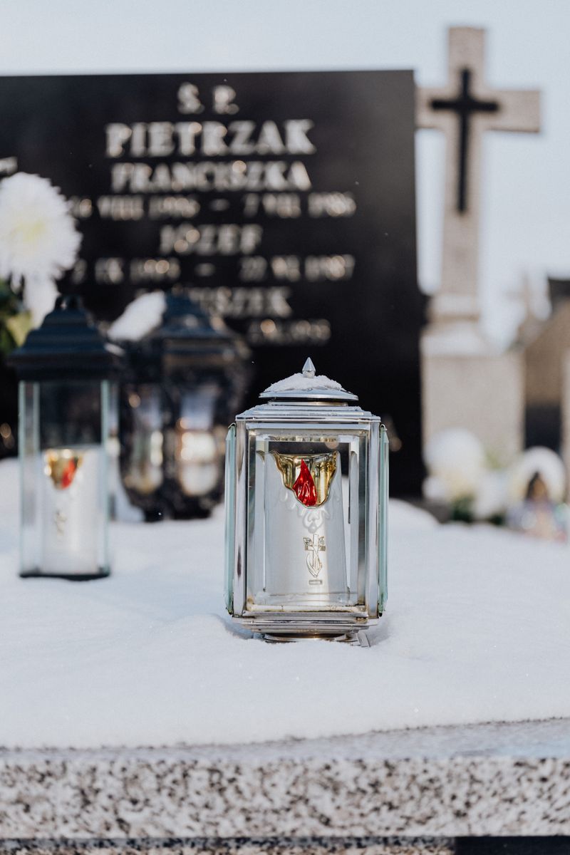 Serene image of snow-laden candle holders at a grave, epitomizing winter tranquility.