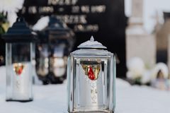 Serene image of snow-laden candle holders at a grave, epitomizing winter tranquility.