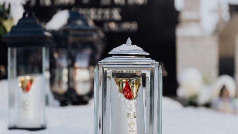 Serene image of snow-laden candle holders at a grave, epitomizing winter tranquility.
