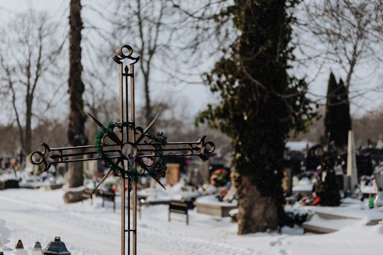 Metal Crucifix In A Snowy Cemetery