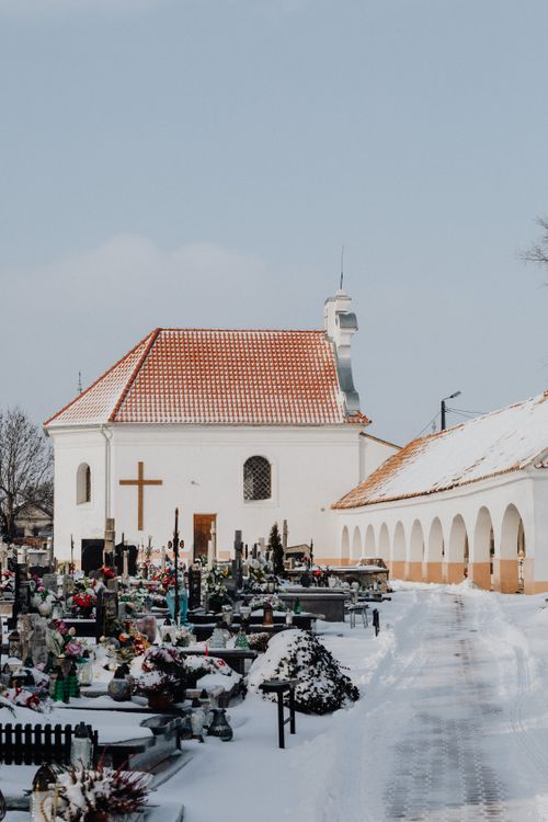 Free Peaceful snowy cemetery beside a historic chapel, under a clear winter sky. Stock Photo