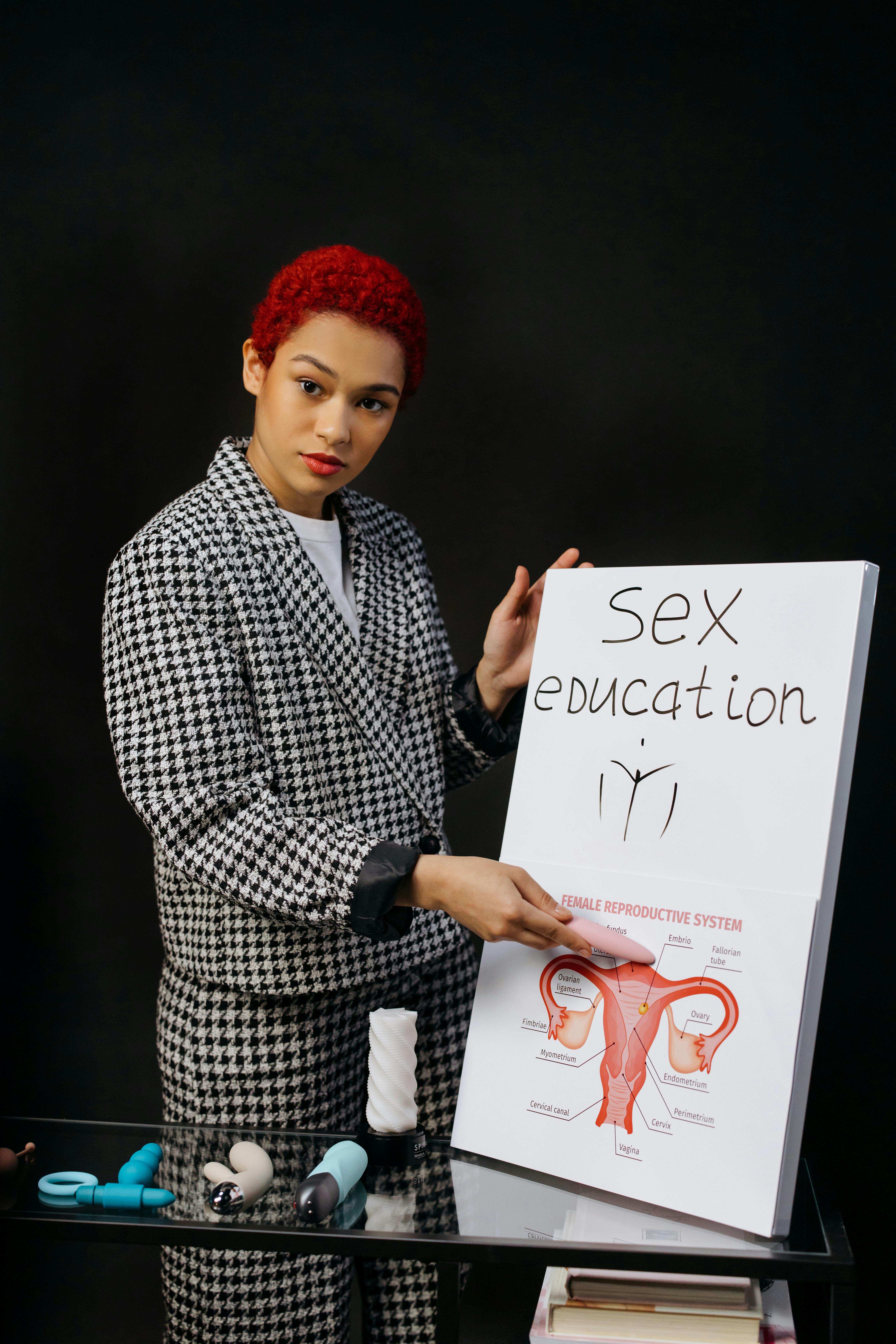 a woman in formal attire holding a white carboard with graphics while looking at the camera