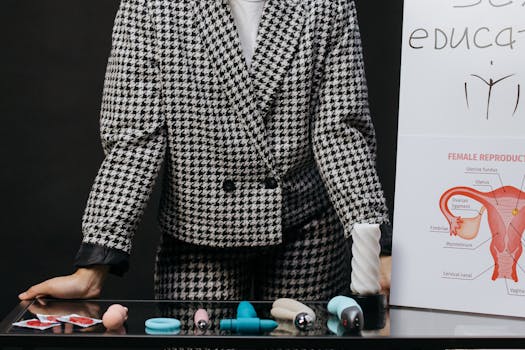 A visual setup for sex education featuring a variety of sex toys and educational materials on a glass table.