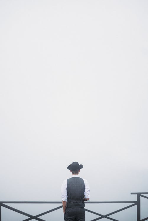 Back View of a Man Standing by the Railings during Foggy Weather