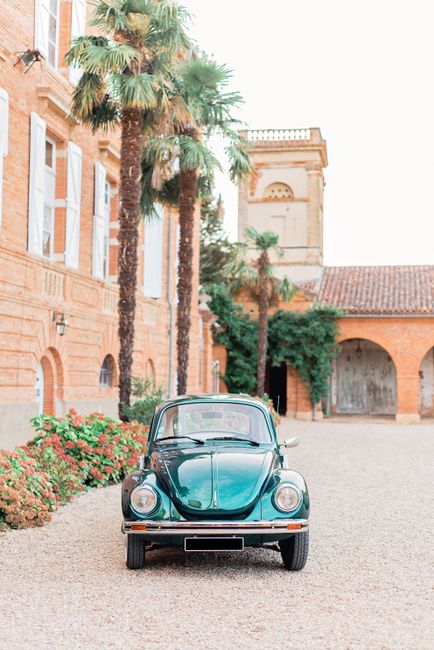 Shiny vintage car parked near tall palms and aged Baroque styled villa with arched passage on sunny day