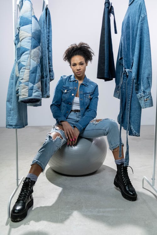 Woman in Denim Clothes near a Clothing Rack