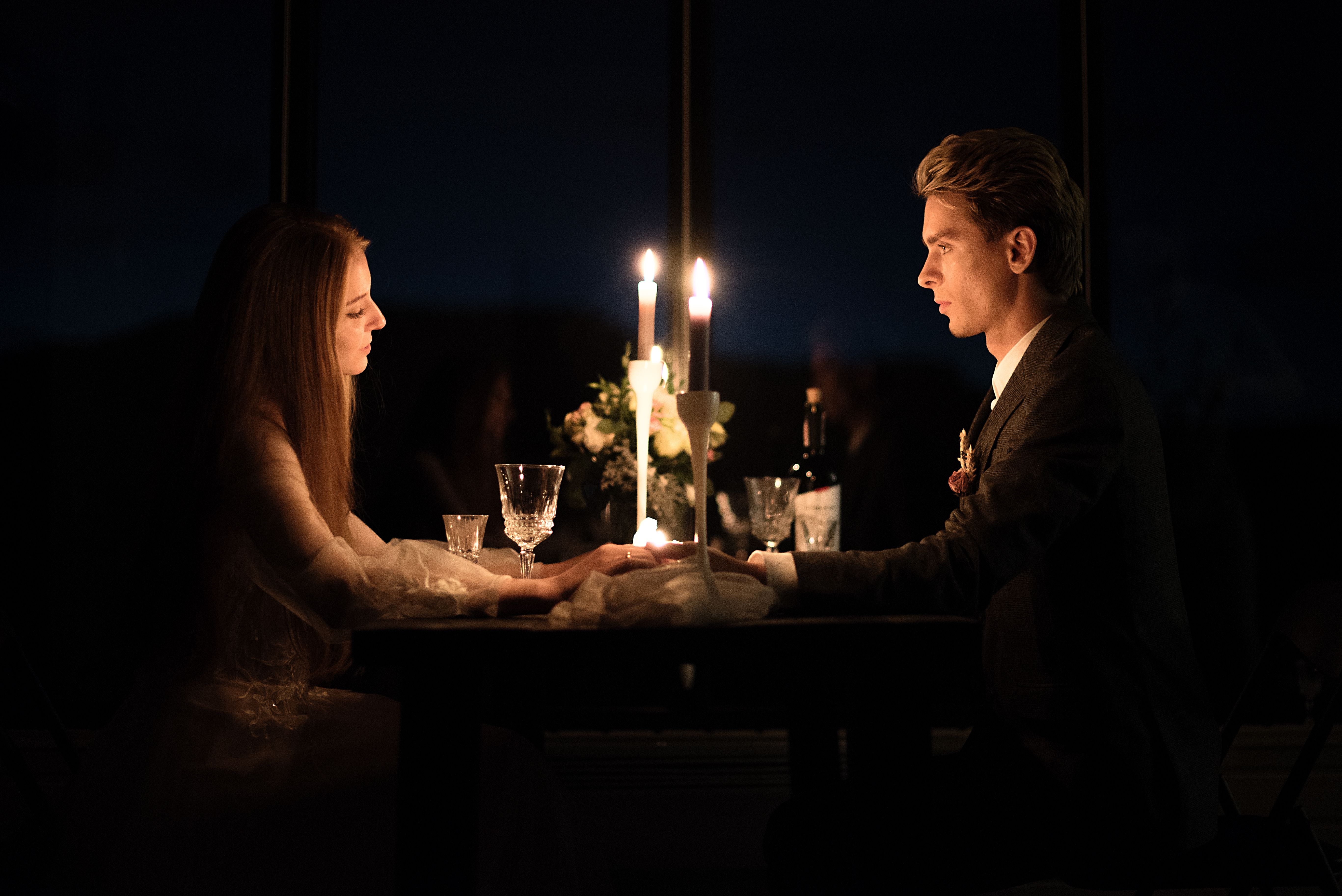 Young elegant couple holding hands during romantic dinner in restaurant