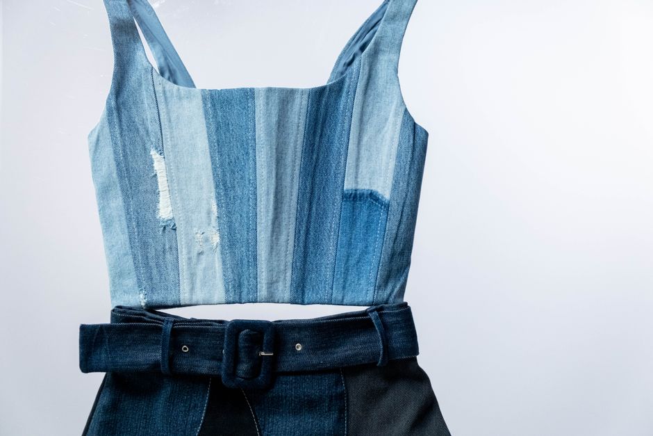 Close-up of a denim dress with a belt, highlighting fashion elements.