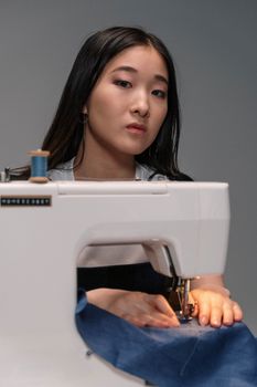 Young woman working attentively on a sewing machine indoors.