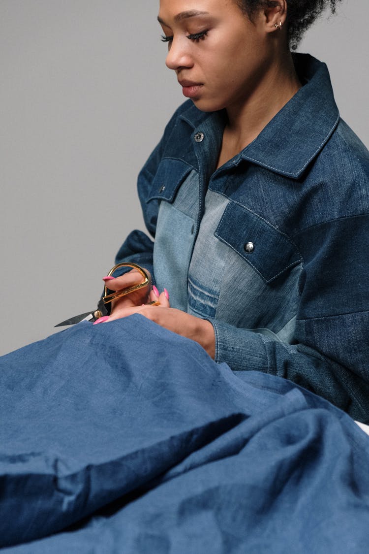 Woman In Denim Clothes Cutting Fabric