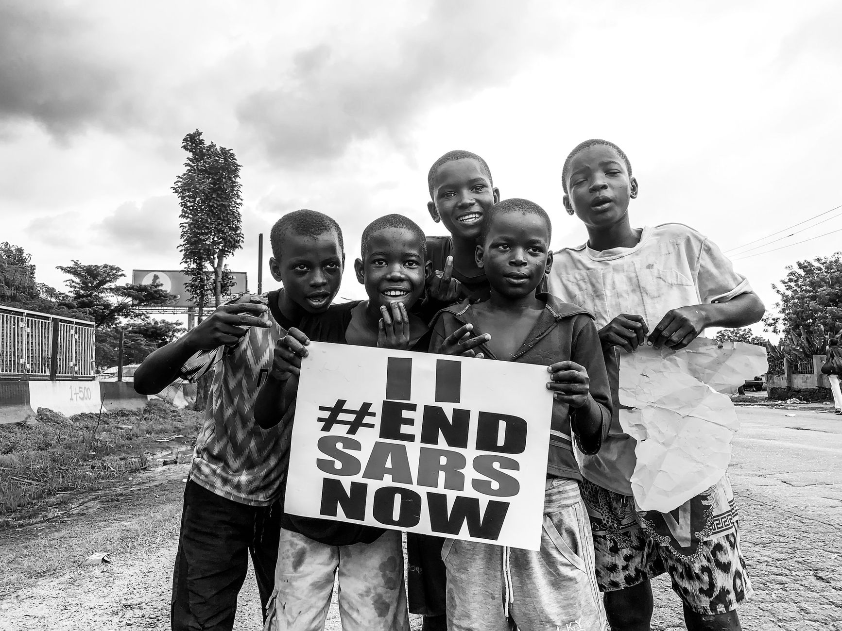 Group of African boys holding an End SARS sign, part of a protest against police brutality.