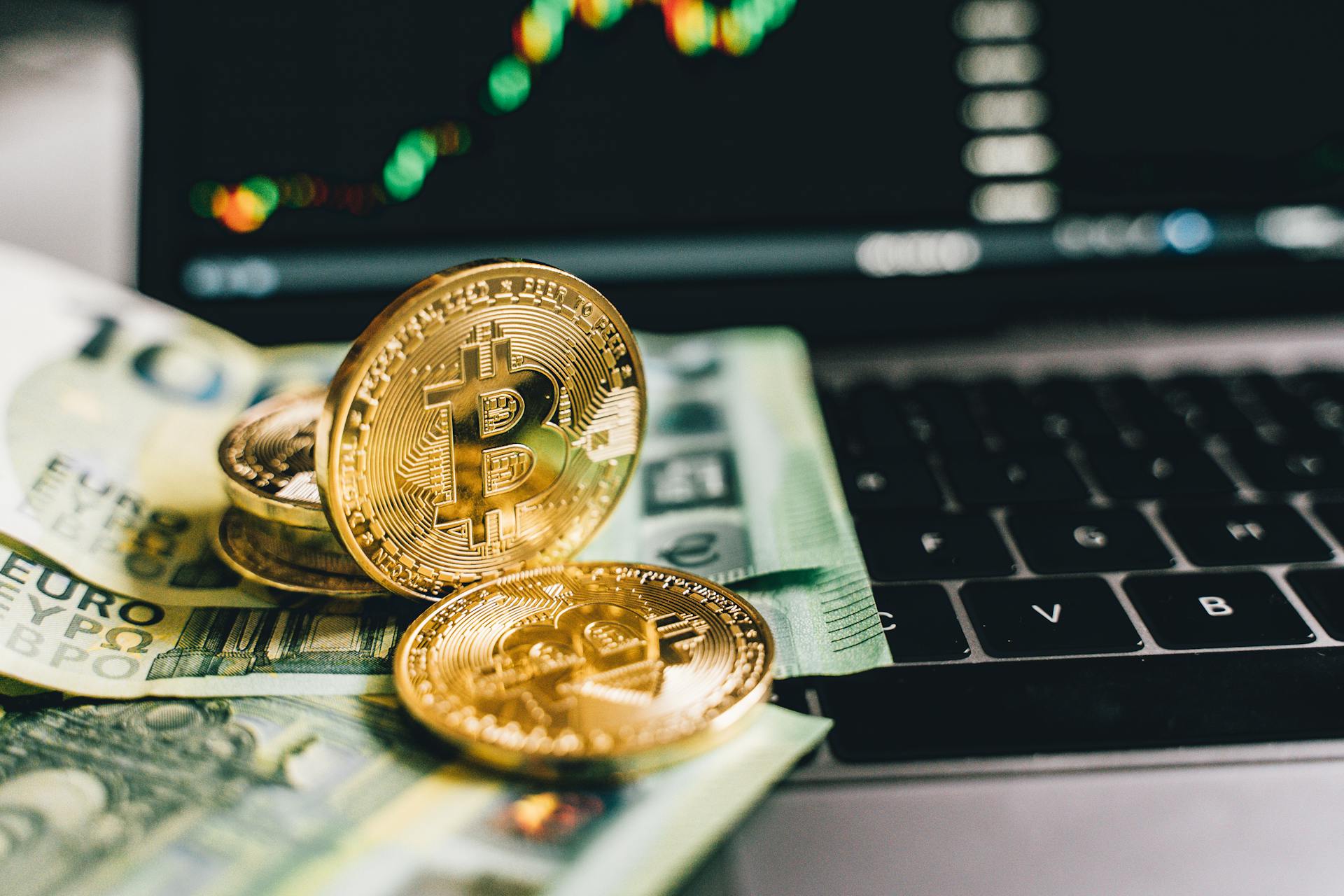 Close-up Shot of Gold Coins and Paper Money on the Keyboard of a Laptop