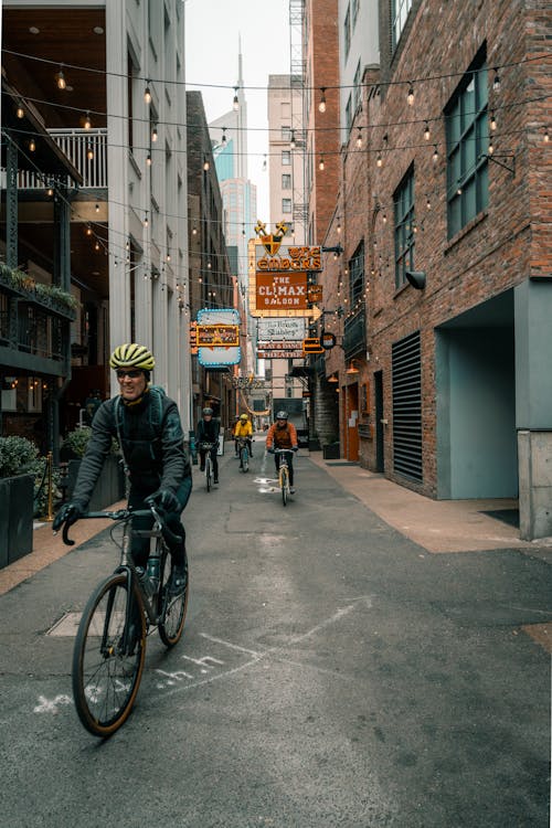 Cyclists Strolling on the Street Between Buildings
