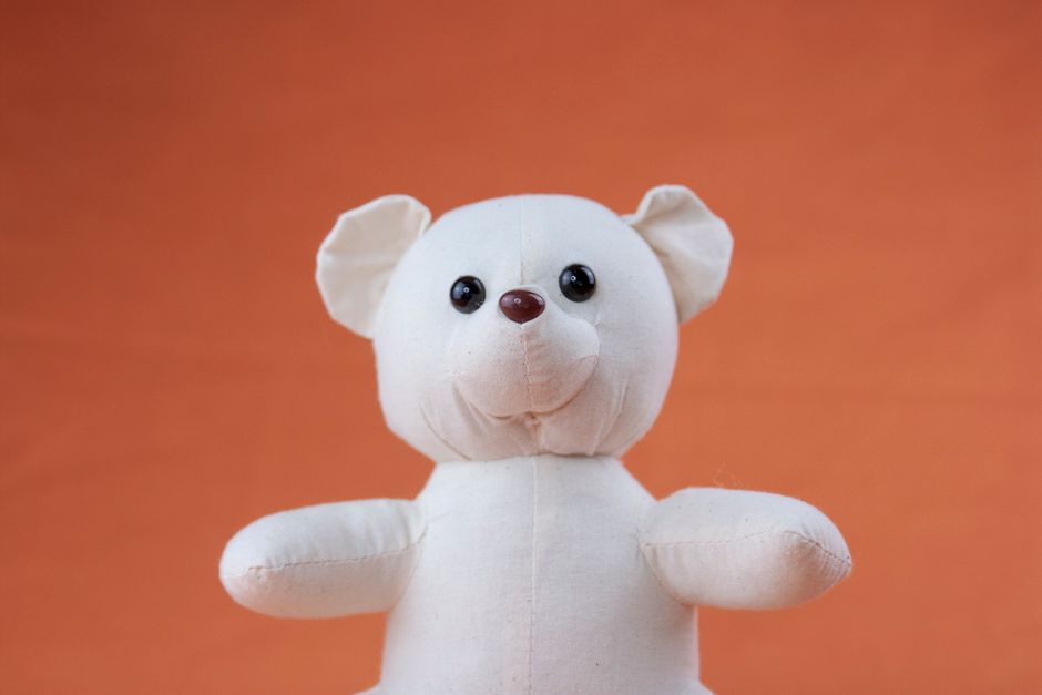 Cute stuffed teddy bear against an orange background, perfect for child-related themes.