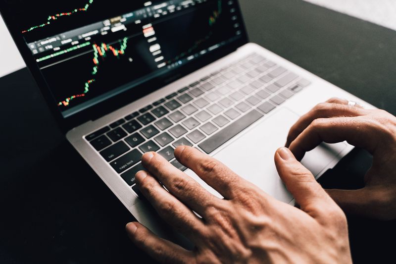 Hands typing on a laptop showing financial charts — photo by Alesia Kozik on Pexels