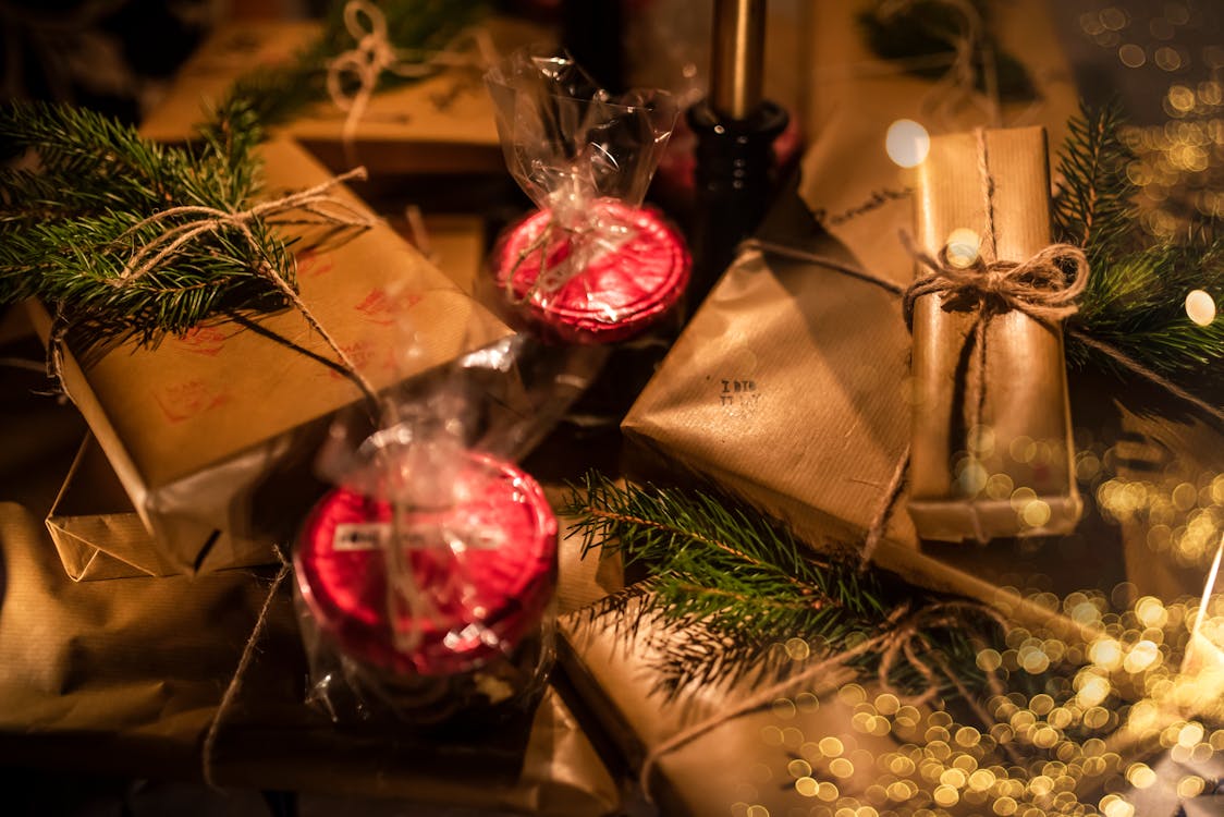 Free Various present boxes in wrapping paper with decorative candles and coniferous tree sprigs during New Year holiday Stock Photo