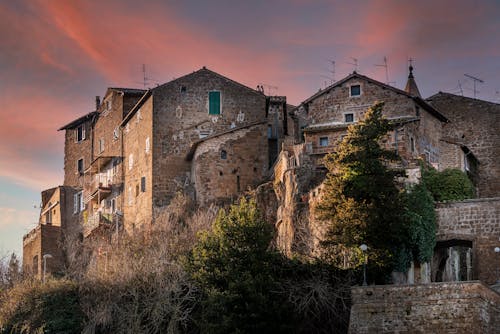 From below of aged stone houses of Calcata medieval town located on hill top under amazing sundown sky