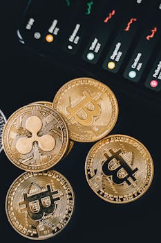 A detailed view of Bitcoin and Ripple coins with market data on a screen, symbolizing digital currency trends.
