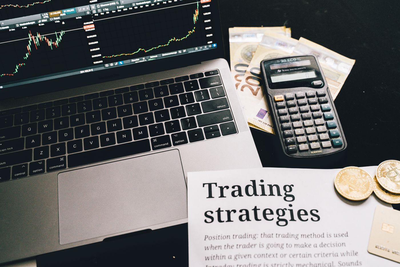 Trader studying trading strategy costs using charts laptop and calculator