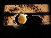 A Cup of Coffee on a Wooden Surface with Scattered Coffee Granules