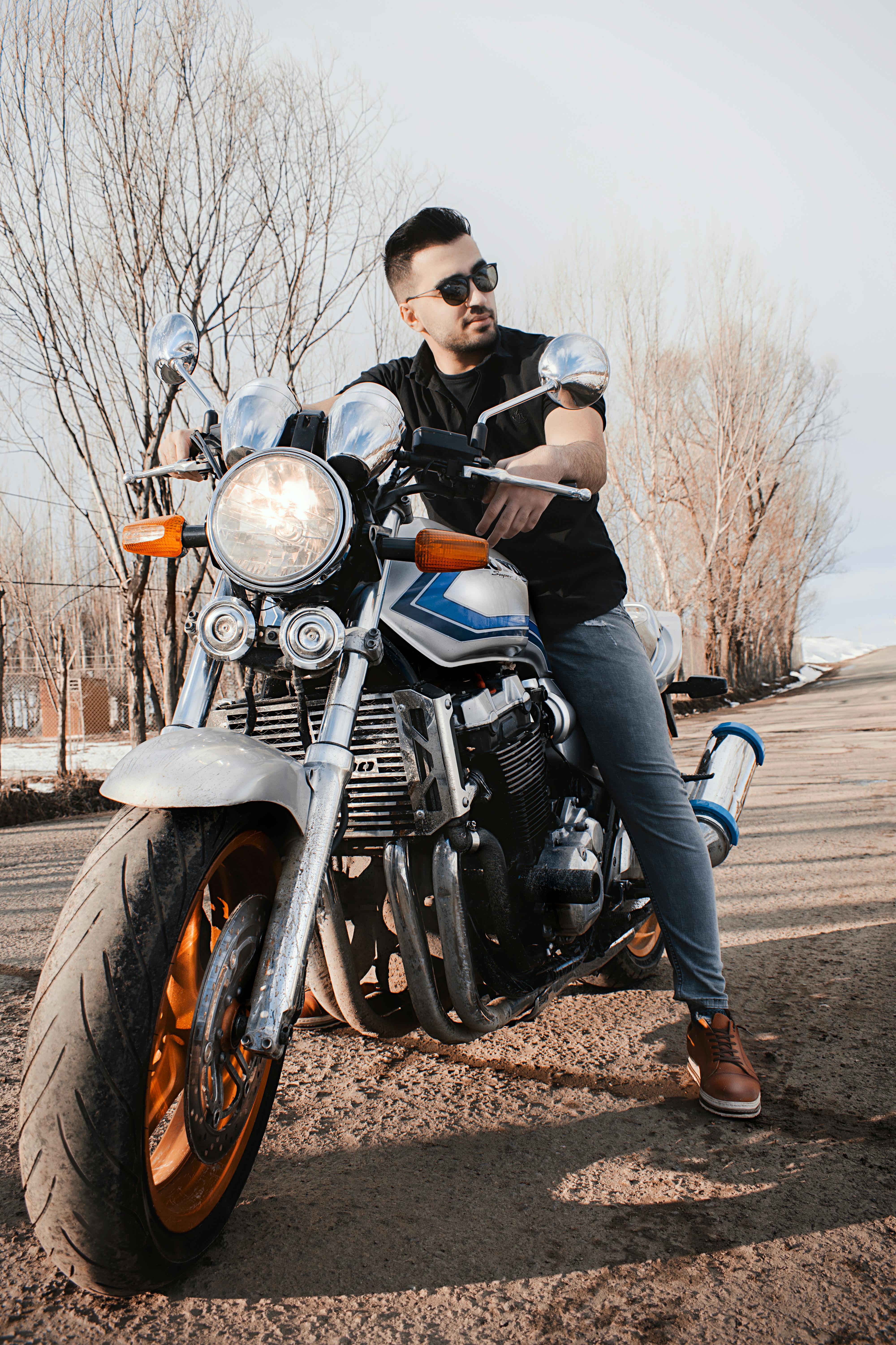 Outdoor portrait of a stylish man on a vintage motorcycle, exuding an adventurous vibe.