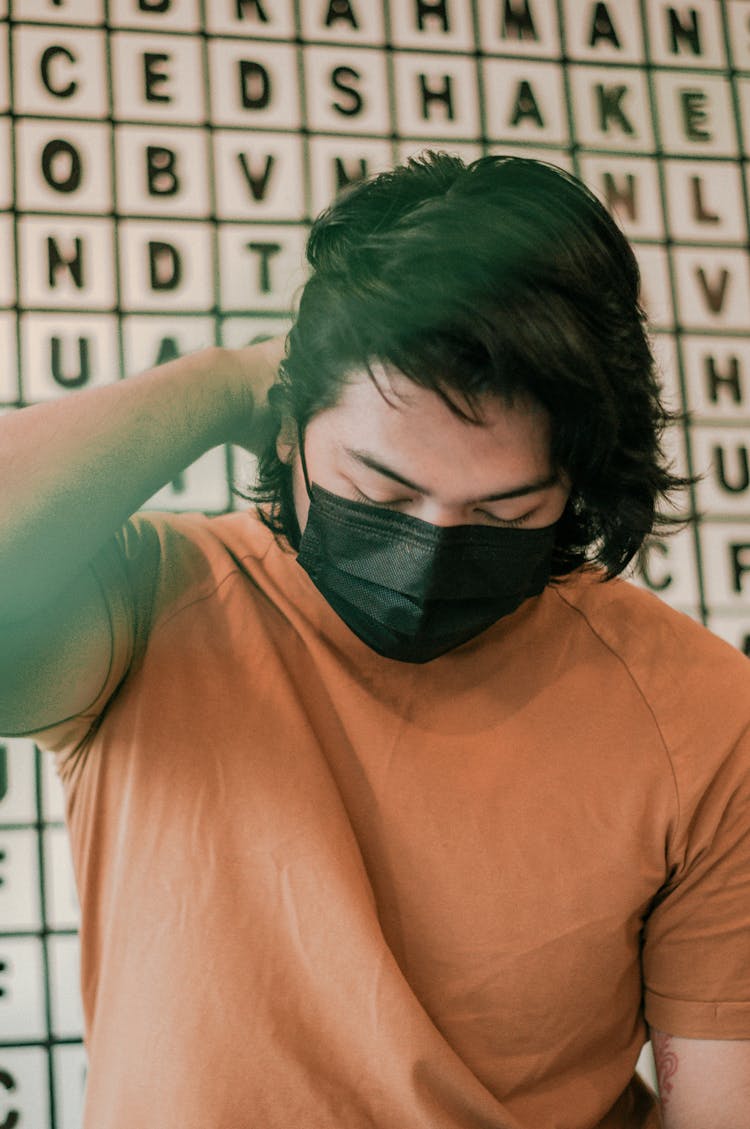 Asian Man In Protective Mask Sitting Near Wall In Cafe