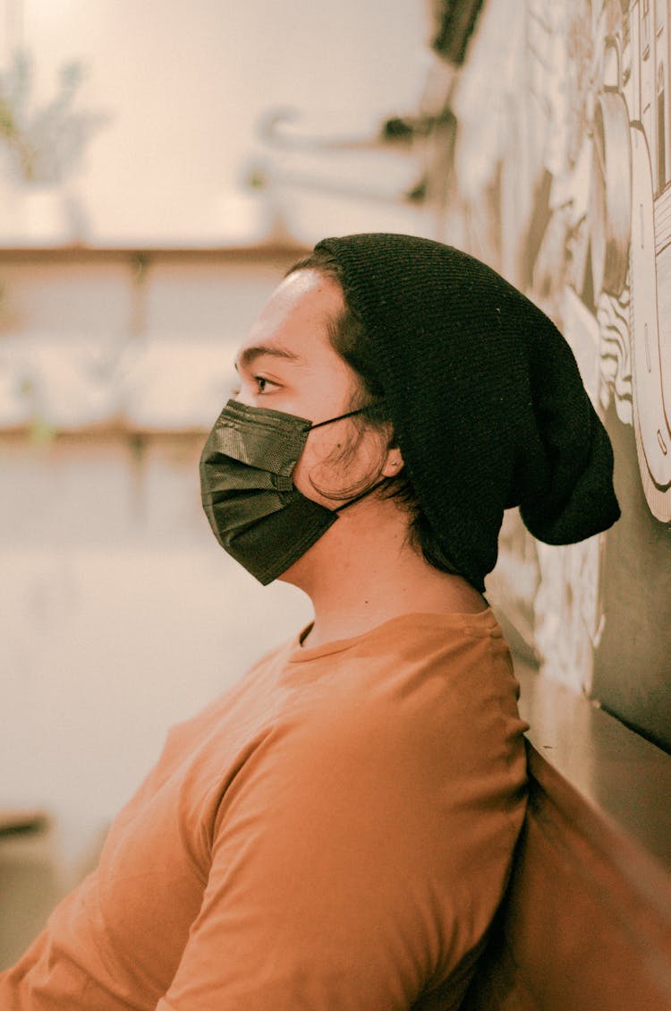 Serious Asian Man In Hat And Protective Mask In Cafeteria