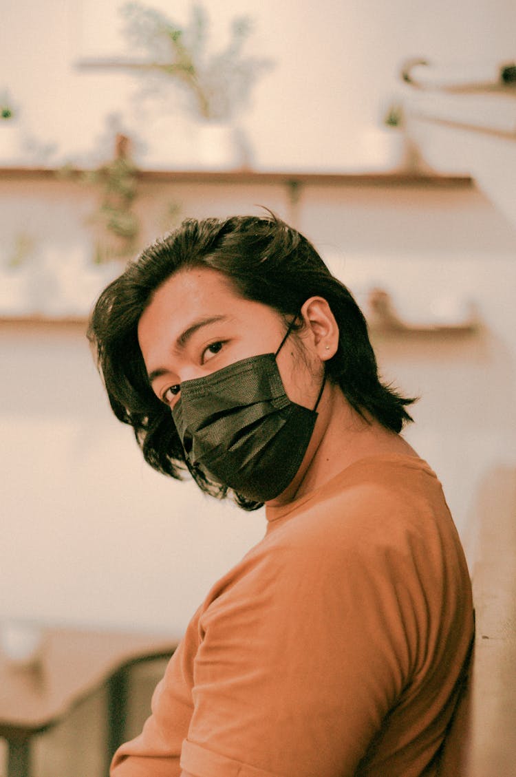 Thoughtful Asian Man Wearing Protective Mask In Cafeteria