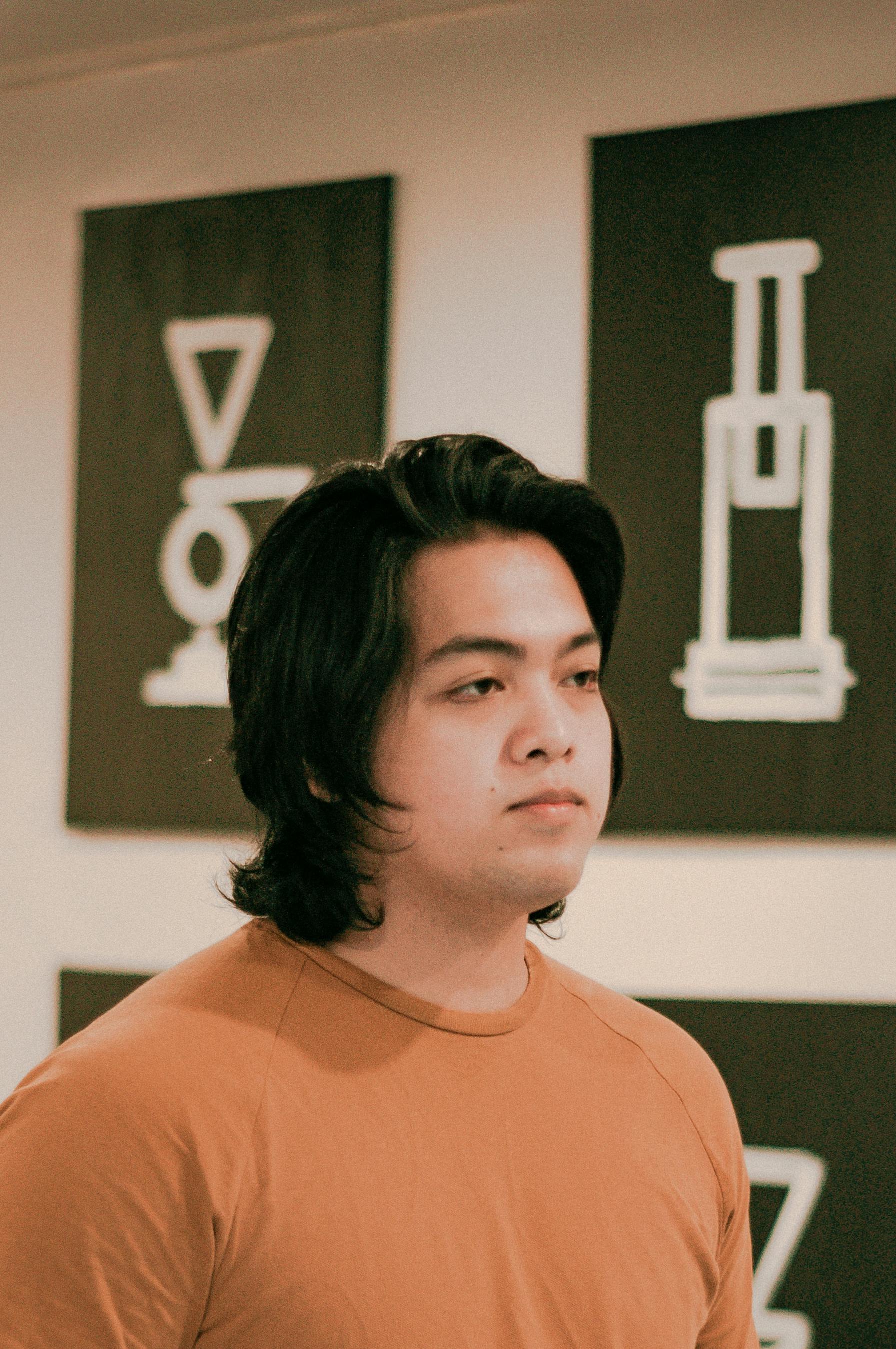 thoughtful young asian man looking away while standing in modern coffee shop