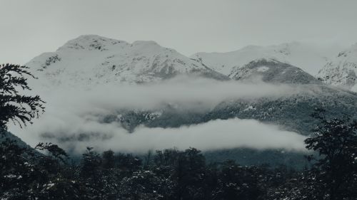 Free A tranquil view of snow-capped mountains enveloped in gentle fog, creating a serene natural scene. Stock Photo