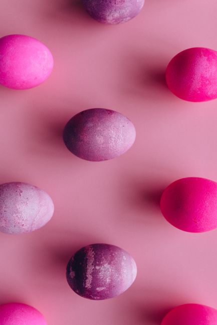 Colorful Easter eggs arranged in a flat lay on a pink surface.