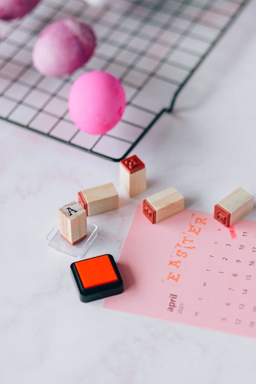 Free Pink Eggs and Brown Wooden Blocks with Stamp Beside a Pink Calendar Stock Photo