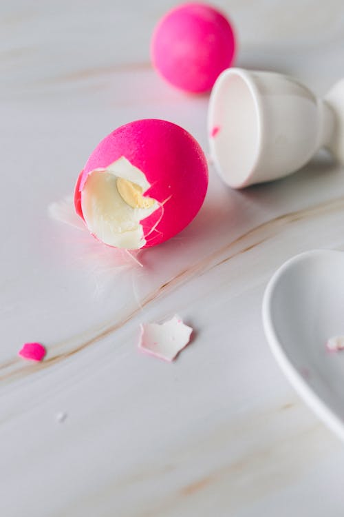 Broken Pink Egg Beside a Ceramic Egg Cup